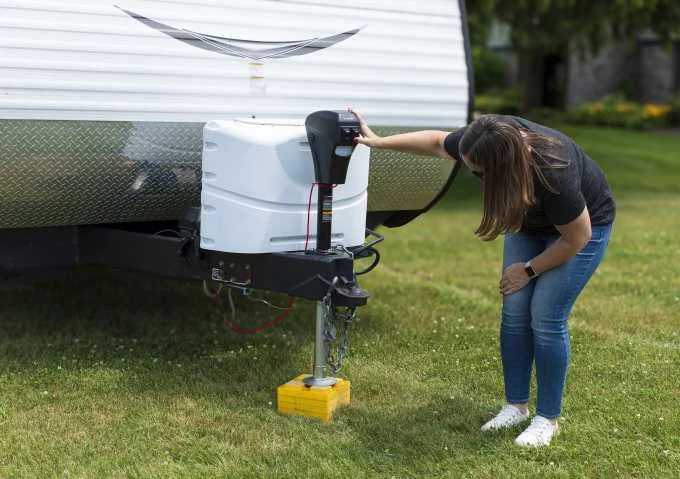 Woman operating a power tongue jack on an RV