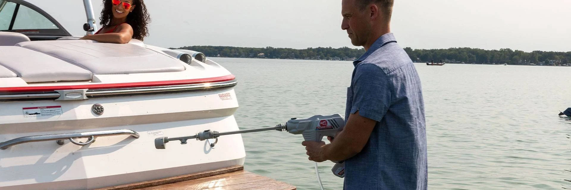 Man Using a Power Washer to Maintain Boat while Woman Watches Man Using a Power Washer to Maintain Boat while Woman Watches