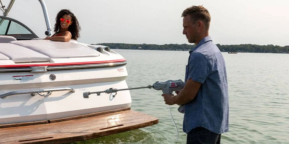 Man Using a Power Washer to Maintain Boat while Woman Watches Man Using a Power Washer to Maintain Boat while Woman Watches