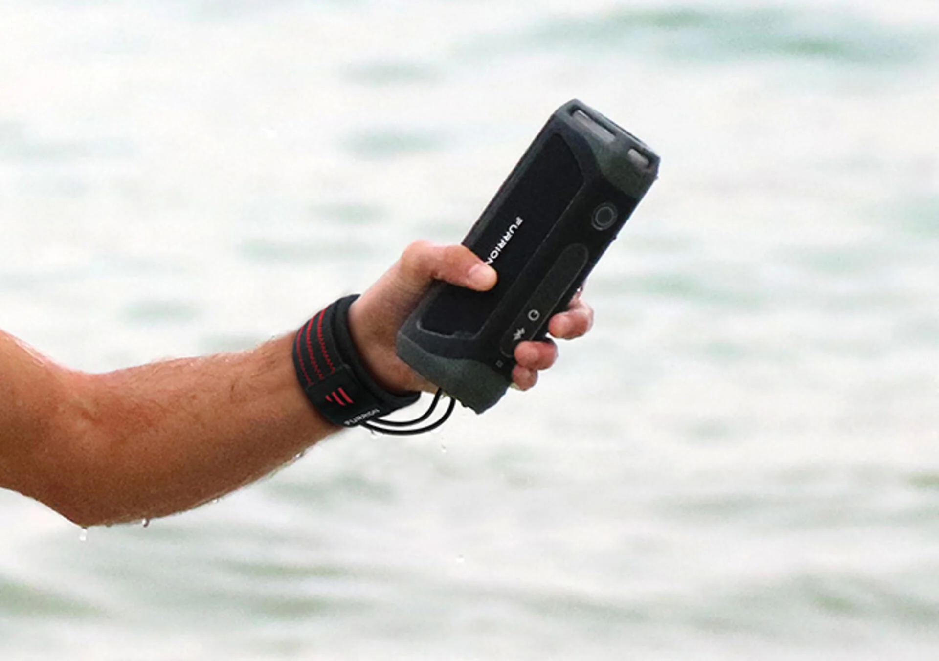 Furrion Bluetooth Marine Speaker Tethered to a Wrist Coming out of the Water