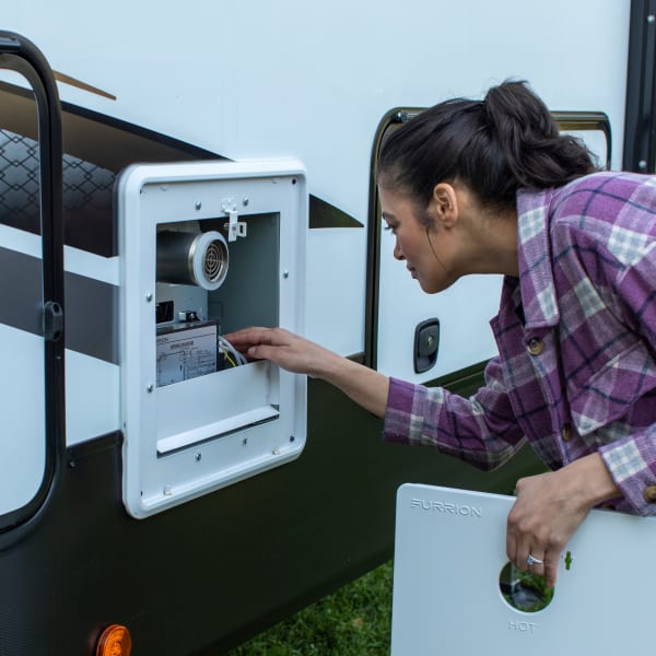 Person adjusting the temperature on a tankless propane RV replacement water heater unit