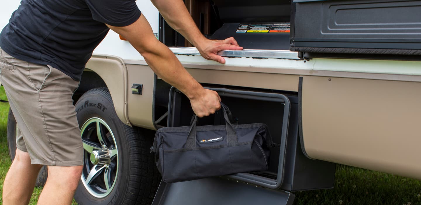 Person putting a duffle bag into an RV storage compartment Person putting a duffle bag into an RV storage compartment