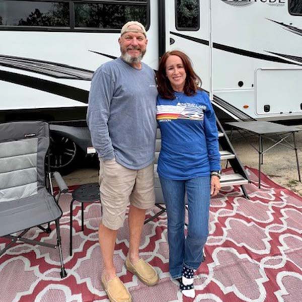 Tammy and Greg cash posing in front of their RV