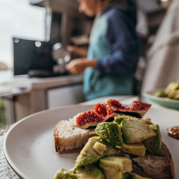 Plate of food in RV kitchen with woman in background